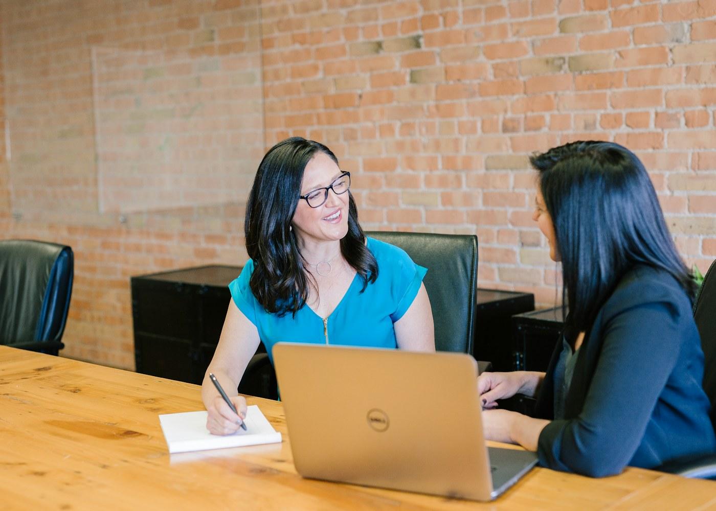 Two colleagues discussing a project around a laptop